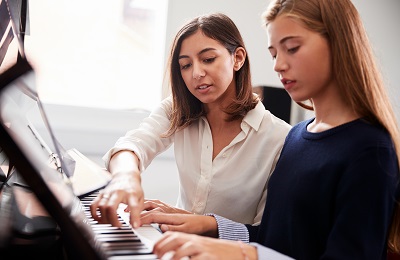 piano teacher and student sitting
        at a piano